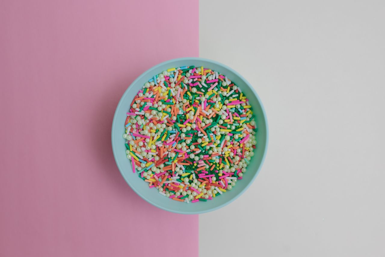 a pastel blue bowl filled with colorful sprinkles on a split pink and
