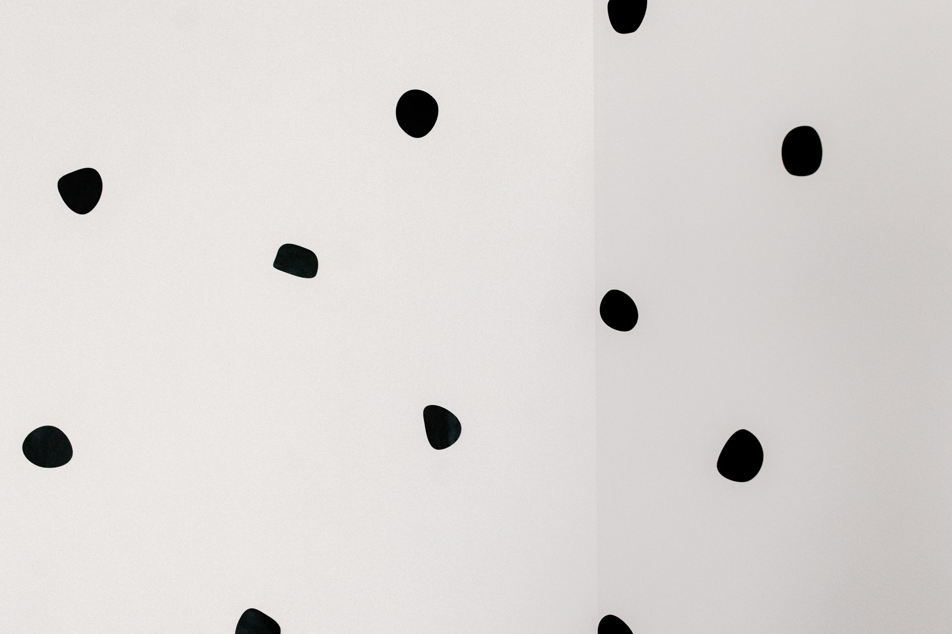 Minimalist image of abstract black dots on a white wall, offering a unique artistic design.