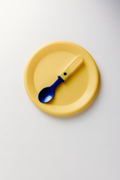 Yellow Handled Blue Plastic Spoon on Yellow Plate