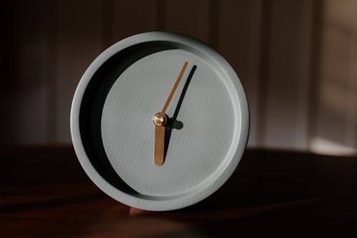 Gray Round Analog Clock on a Wooden Surface