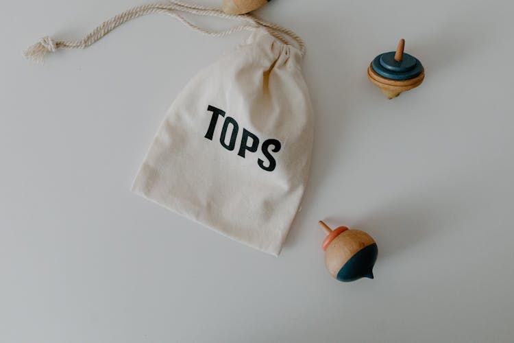 Wooden Toy Tops Beside A String Bag