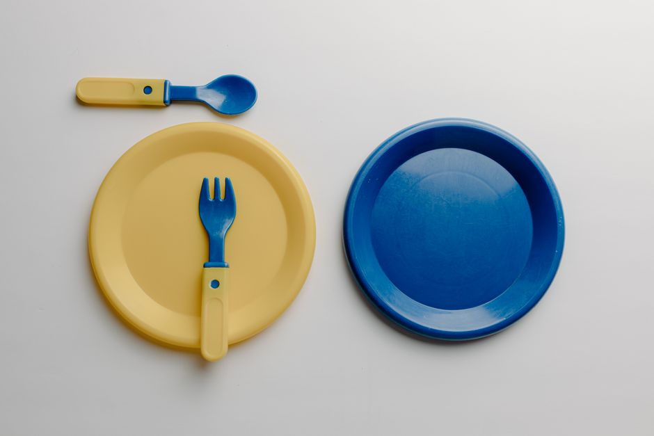 Brightly colored toy plates and utensils arranged on a white background.