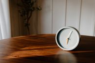 Gray Analog Clock on a Wooden Table