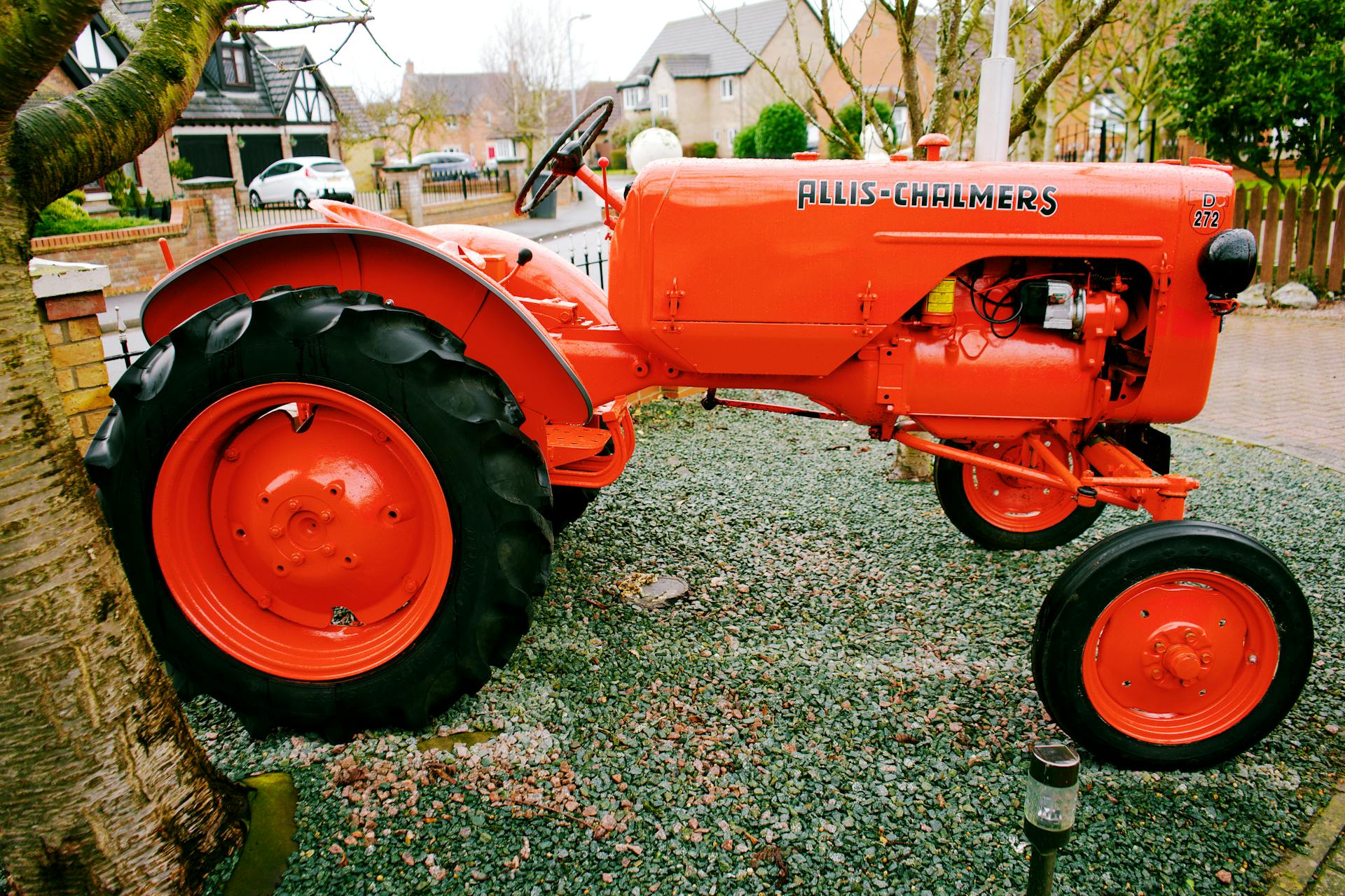 A classic Allis Chalmers tractor showcased in a picturesque English residential setting.