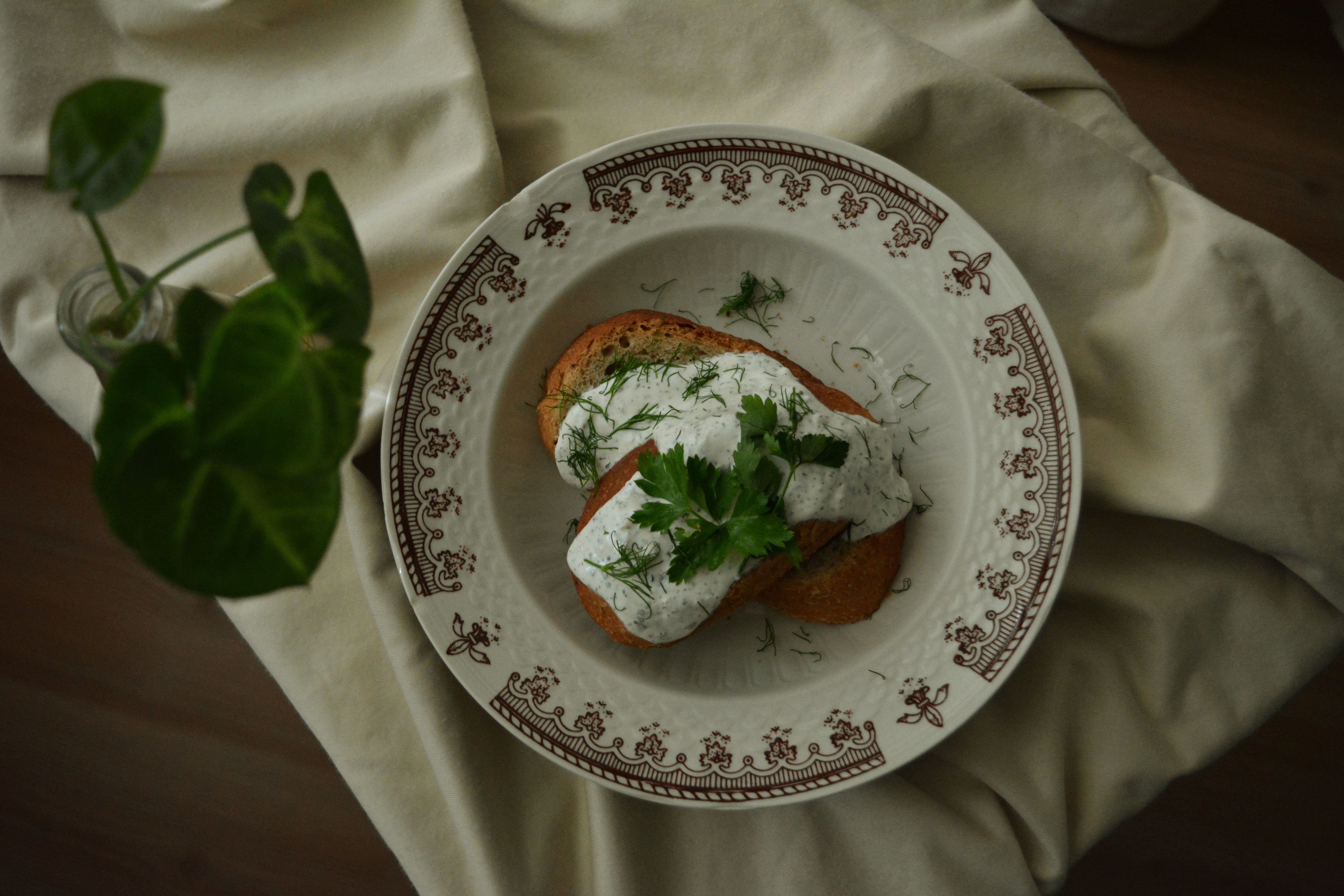 Delicious toasted bread topped with herbal cream and garnished with fresh herbs on a classic ceramic plate. - Photo by Duygu  M on Pexels
