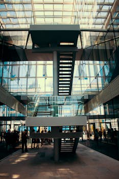 Contemporary building interior with a striking glass facade and central staircase.