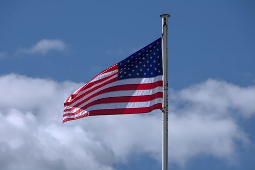 Free United States flag waving proudly against a clear blue sky in Olympia, WA. Stock Photo