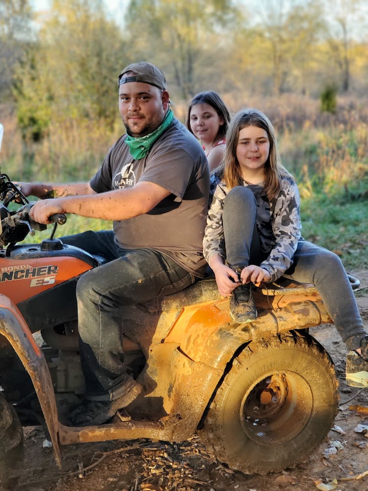 A Man Driving A Muddy Atv