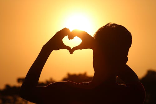 Photo Silhouette De L'homme Faisant Signe De Coeur Pendant L'heure D'or