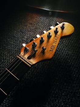 Detailed view of a guitar headstock showcasing tuning keys and wooden finish under warm lighting.