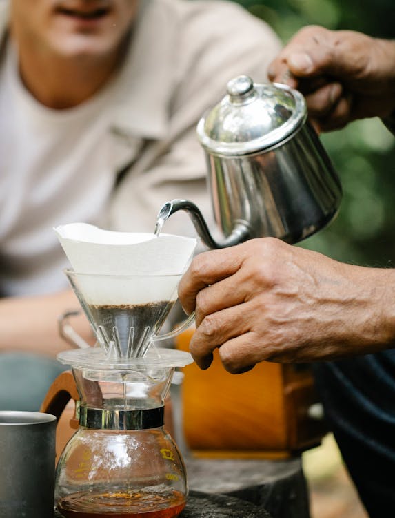 Crop friends with kettle preparing coffee in garden