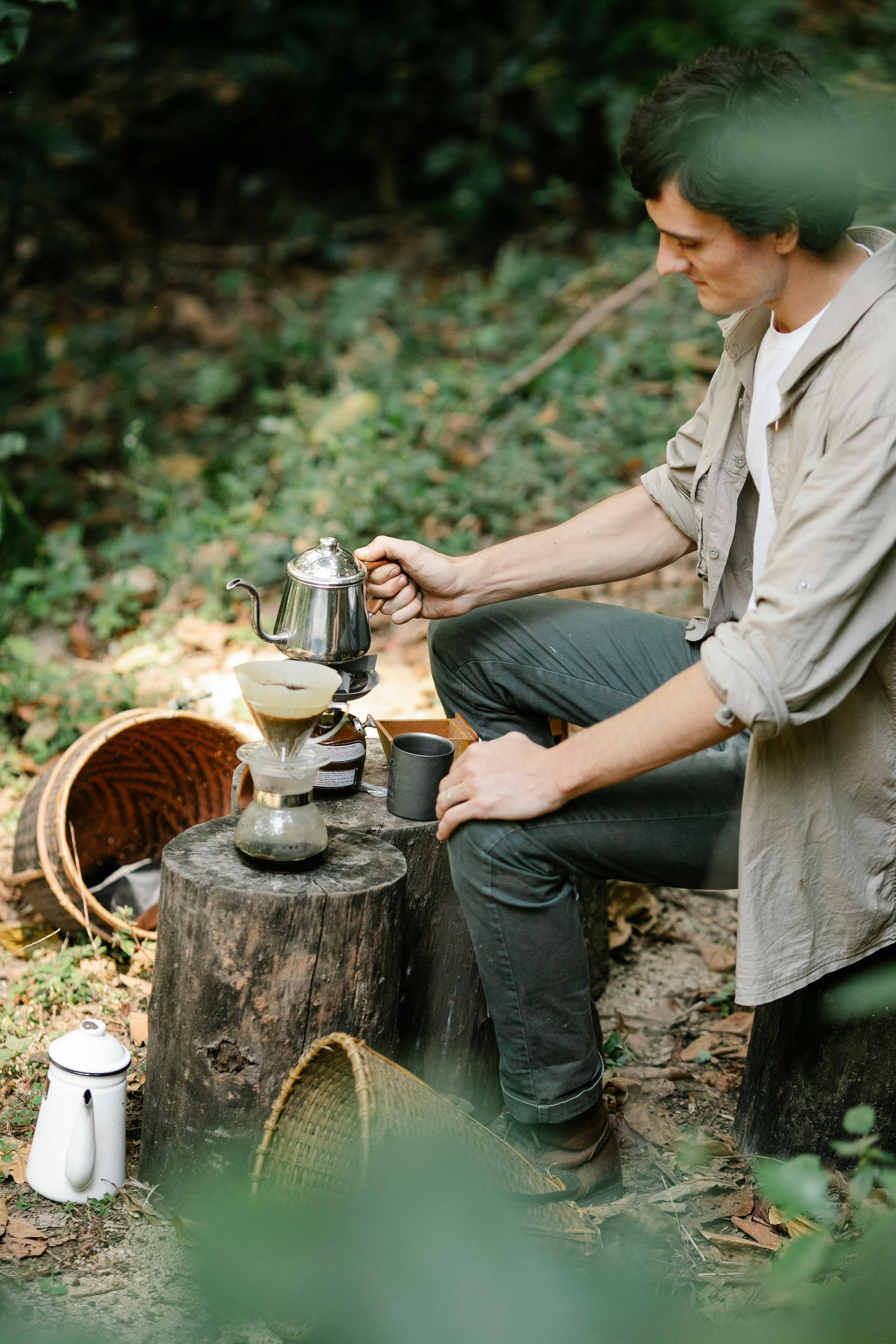 farmer brewing coffee on stump in countryside