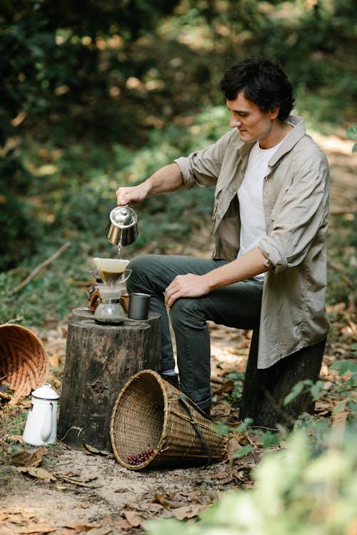 Horticulturist preparing coffee on stump in countryside