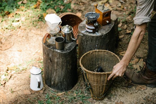 Free From above of crop anonymous male farmer with bucket on pathway against coffee kettle and gas burner on stumps Stock Photo