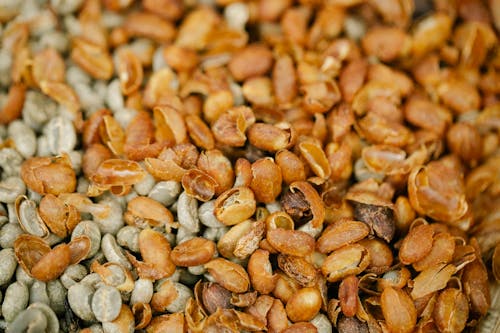 From above of backdrop representing unroasted coffee bean halves with chaff drying on blurred background