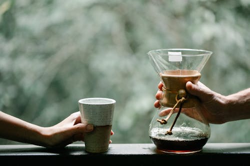 Faceless couple with freshly brewed coffee in jug on veranda