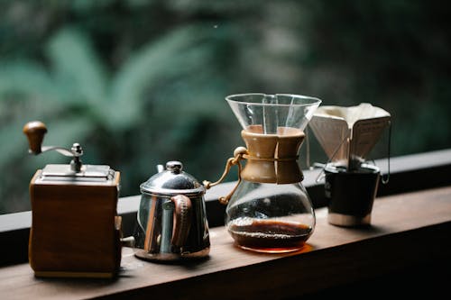 Free Chemex coffeemaker with cup placed on terrace with metal kettle and hand grinder Stock Photo