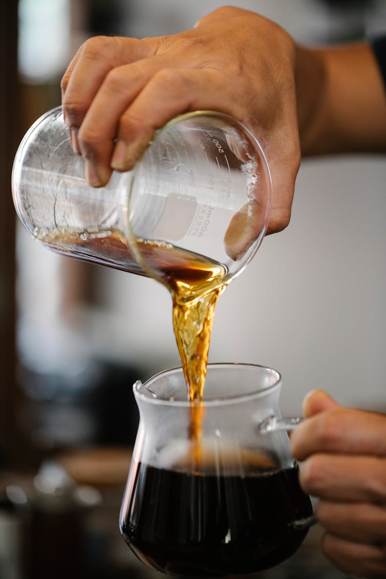 Unrecognizable Man Pouring Fresh Hot Coffee From Pitcher Into Glass Cup