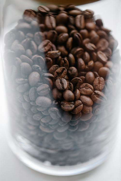 Glass jar with heap of roasted coffee beans