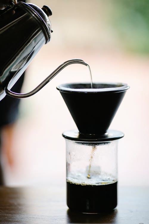 Anonymous barista poring water into cup while brewing filter coffee