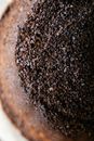 Top view closeup of aromatic roasted ground coffee in cup with paper filter in daylight