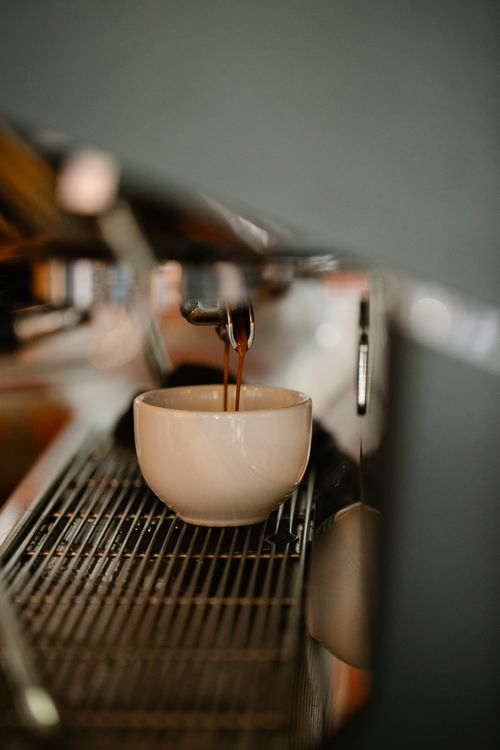 Free Modern coffee machine preparing double shot espresso pouring in white ceramic cup in cafe Stock Photo