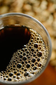 A detailed close-up image of frothy coffee in a clear glass, showcasing bubbles and rich aroma.