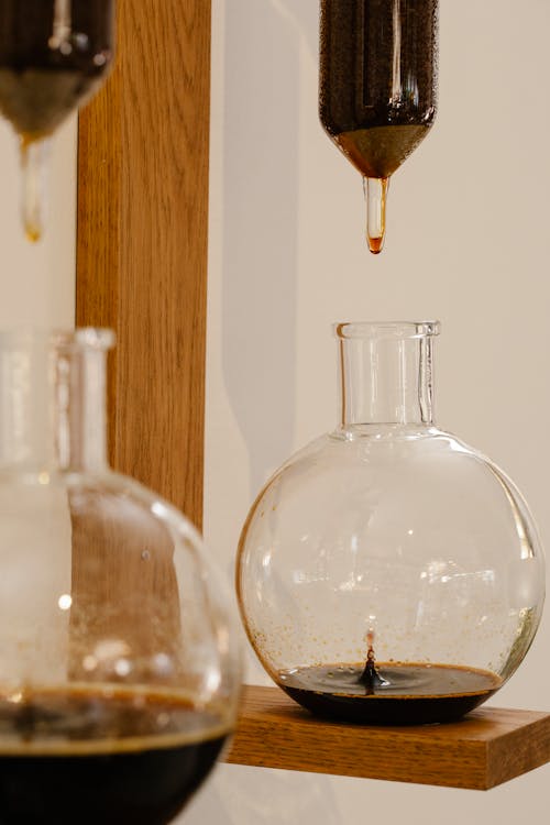 Hoe coffee dropping in syphon makers into glass flasks while standing on wooden board