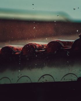 A detailed view of raindrops falling on a tiled roof, capturing the essence of a rainy day.