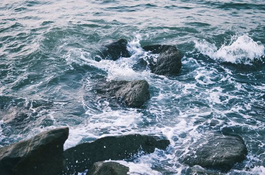 Dynamic ocean waves crashing against rocky shores at Malpe Beach, India, captured with vivid detail.