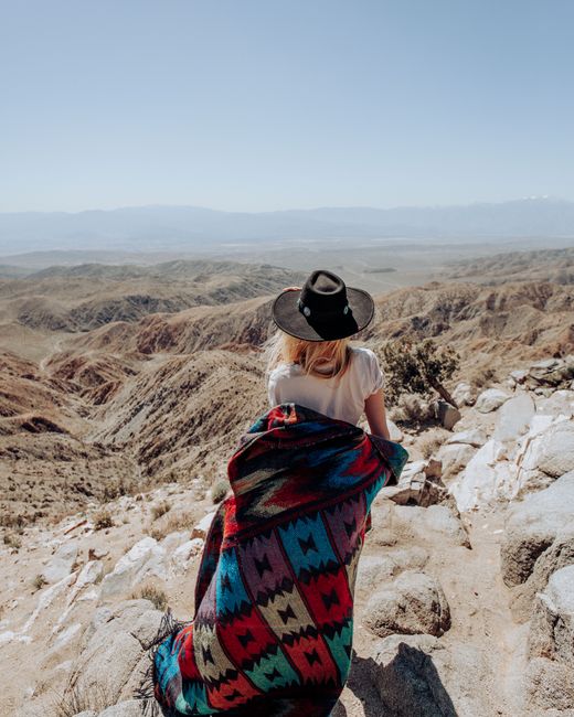 A woman wrapped in a colorful poncho enjoys a desert view in California.