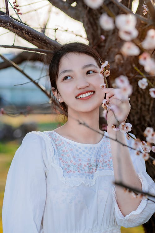 Smiling Woman Standing Next to a Cherry Blossom Tree