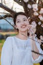 Smiling Woman Standing Next to a Cherry Blossom Tree