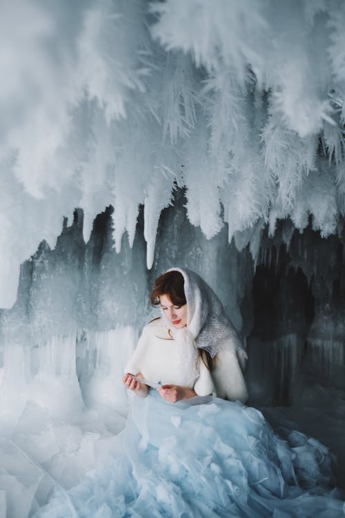 Woman in White Dress Sitting on Snow Covered Ground