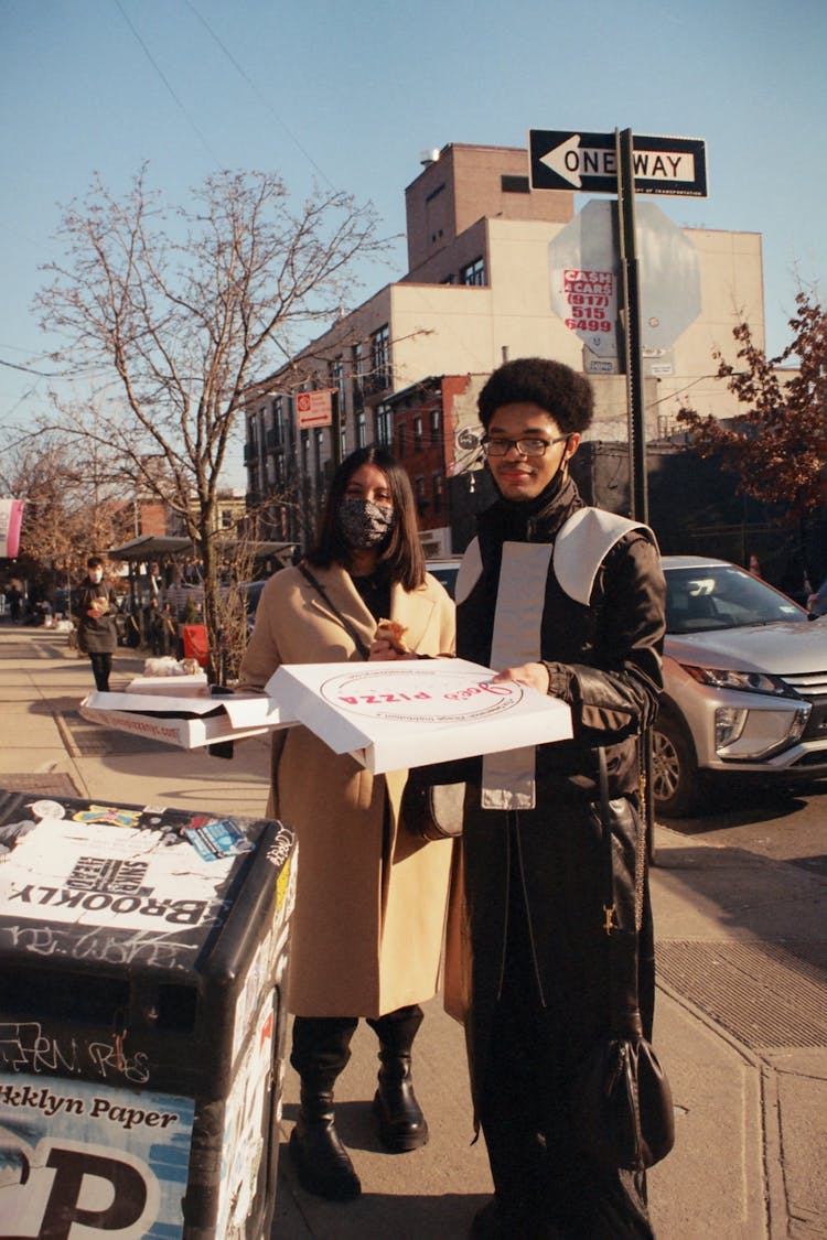 Photo Of A Man Holding A Pizza Box Near A Woman