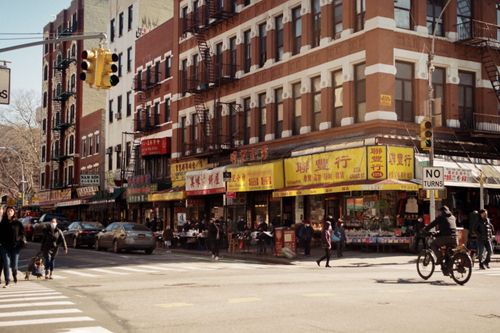 Free Busy intersection in NYC's Chinatown, capturing pedestrians and shops in a lively urban setting. Stock Photo