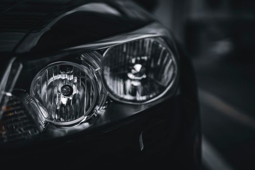 Detailed close-up of a car headlight showcasing design and texture in black and white.