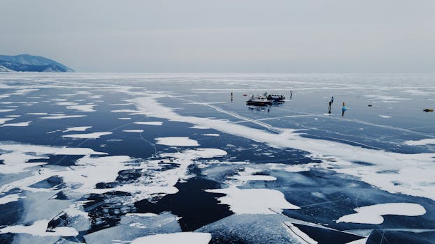 Aerial view of a frozen Lake Baikal with snow and ice formations, travelers exploring the surface.