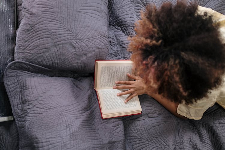 A Person With Afro Hair Reading A Book