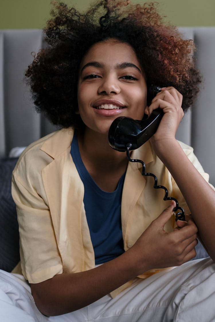 An Afro-Haired Woman Using A Telephone