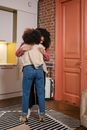 Woman in Pink Long Sleeve Shirt and Blue Denim Jeans Standing Beside Brown Wooden Door