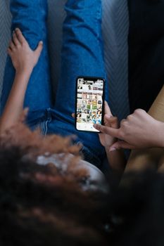 Overhead view of young women using a smartphone while relaxing indoors.