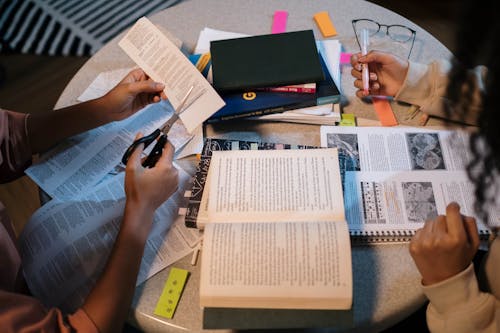 Girls Sitting at the Table with Textbooks and Studying