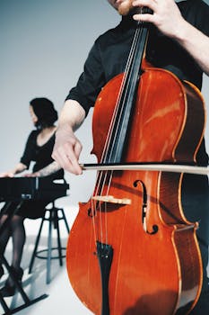Duo playing cello and keyboard indoors in a modern setting.