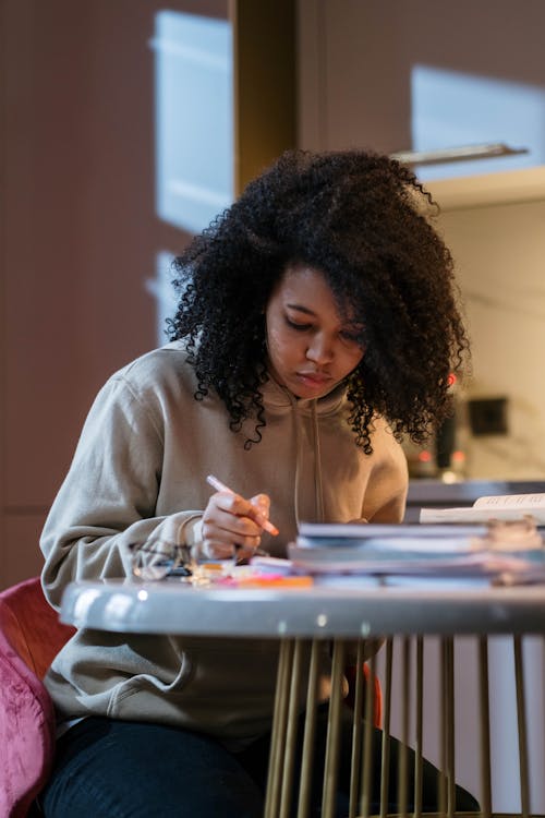 Free Girl Sitting at the Table with Textbooks and Studying  Stock Photo