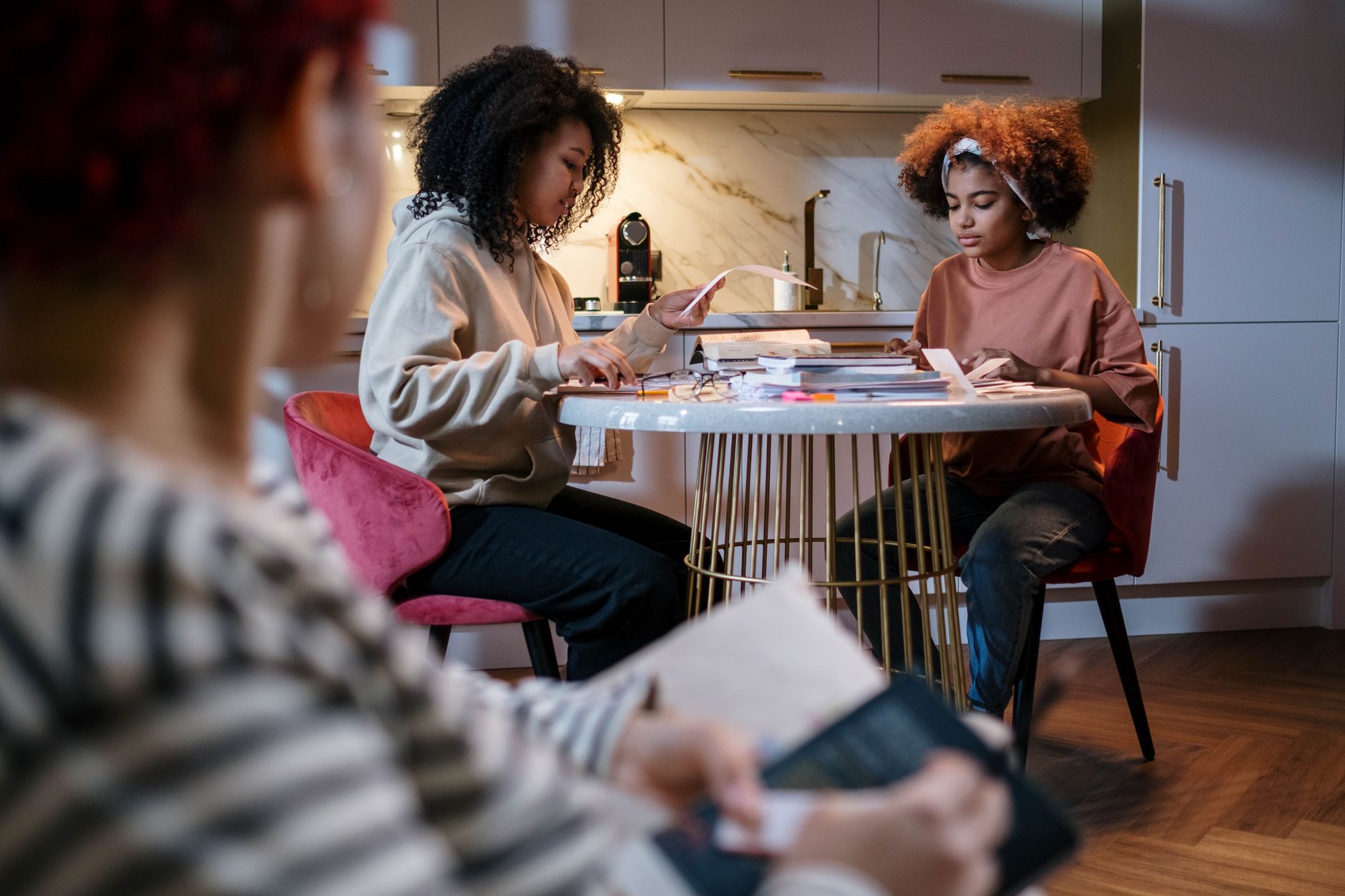 Roommates reviewing notes at a kitchen table before sharing an apartment