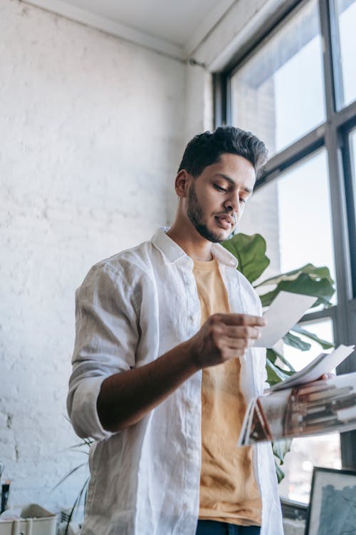 Focused ethnic man looking at photos in light room