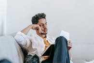 Unemotional ethnic man sitting on sofa with diary