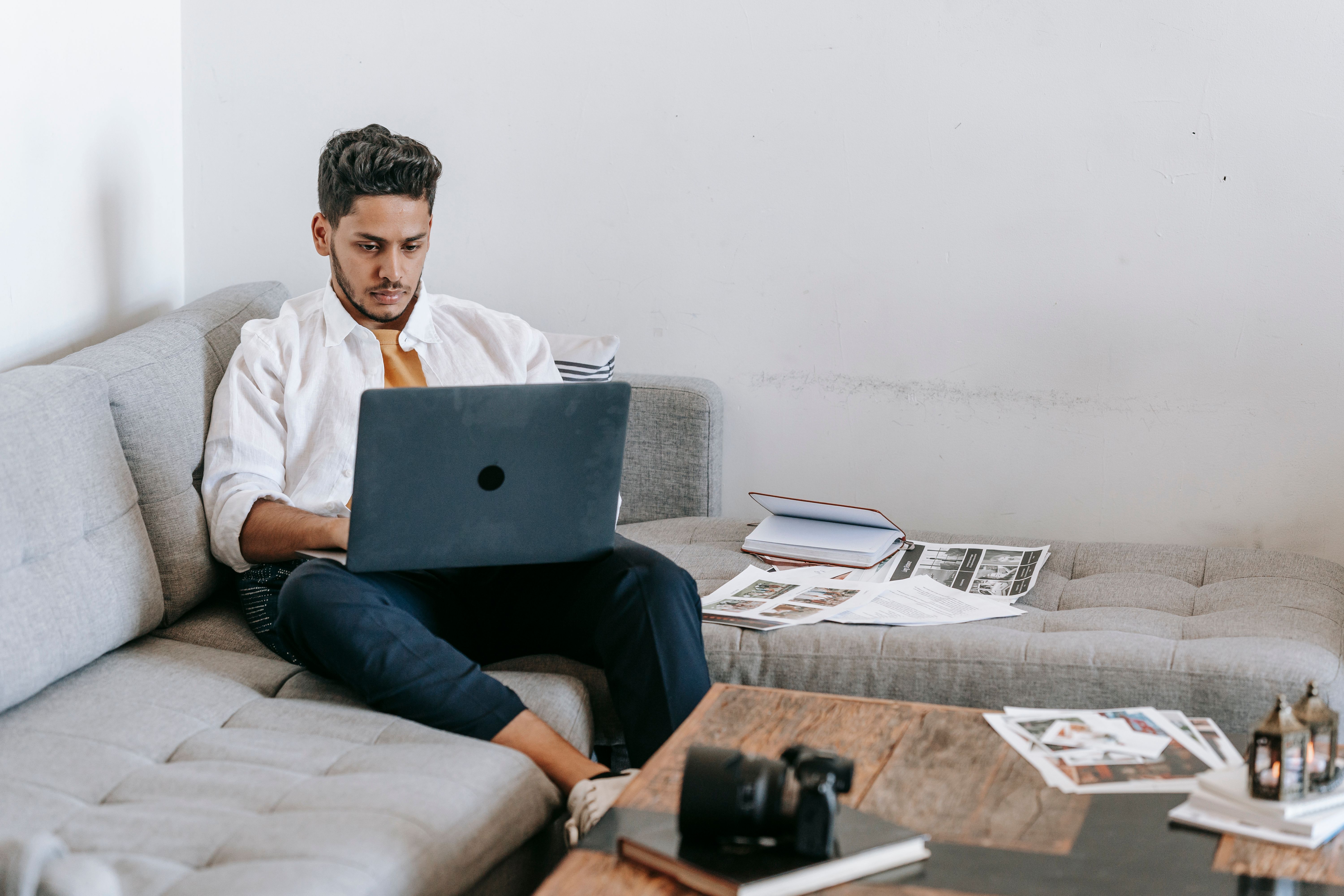 Man working on a laptop in a cozy living room with a focus on digital work and comfort.