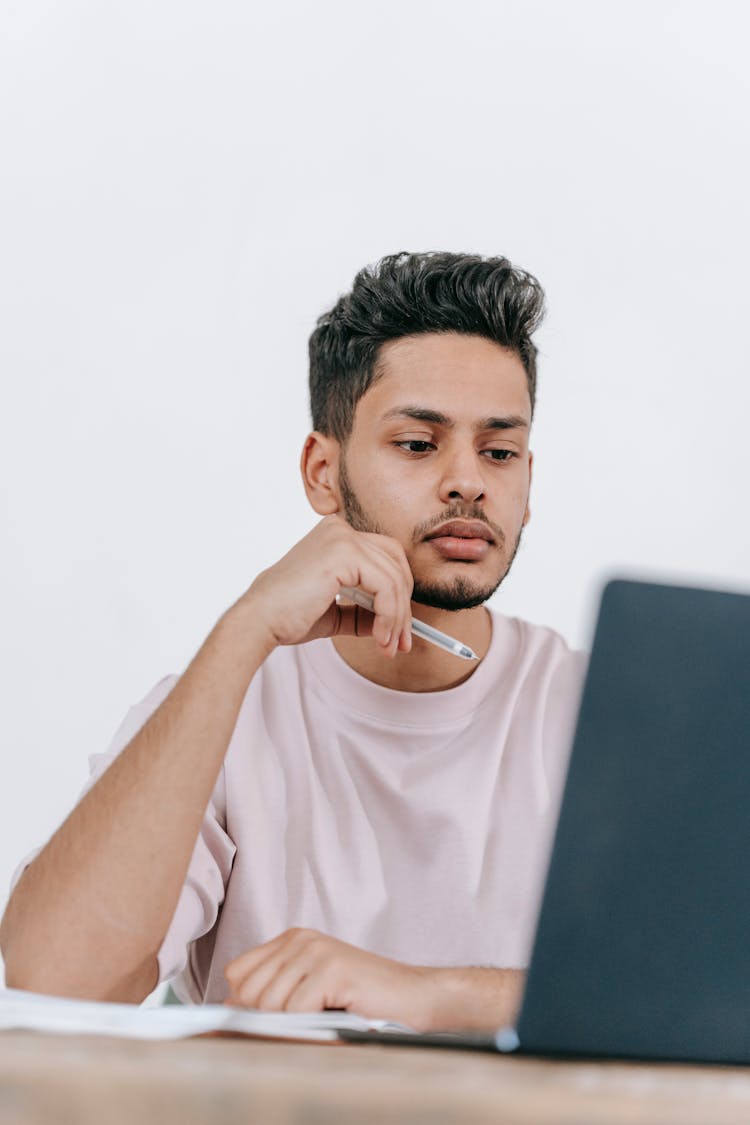 Young Ethnic Man Working On Laptop And Writing Notes